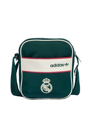 Bolso bandolera verde oscuro con franja horizontal blanca, logo de Adidas y emblema del Real Madrid; correa ajustable para el hombro y cierre de cremallera.