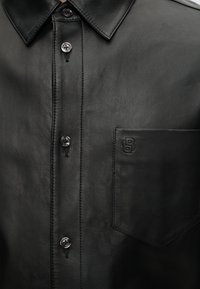 Μαύρο δερμάτινο πουκάμισο με κουμπιά, με μυτερό γιακά και τσέπη στο στήθος με ανάγλυφο διασταυρούμενο λογότυπο "SB".