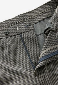Hahnentrittmuster-Hosen in Marineblau und Grau, mit Knopfverschluß, Reißverschluss und kontrastierender Innenseite. Glatte Textur.
