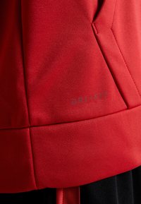 Camiseta atlética roja Dri-FIT con una textura suave y detalles en las costuras. Logotipo impreso en gris cerca del dobladillo. Tejido elástico para mayor comodidad y movimiento.