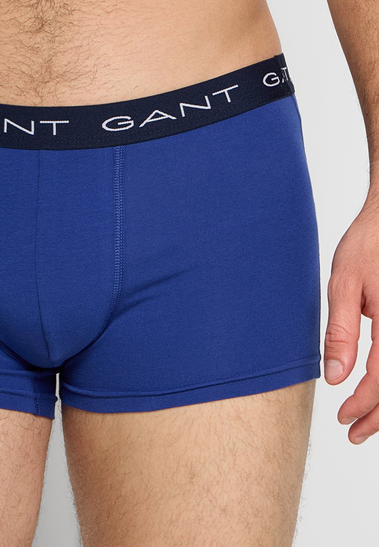 Blå boxershorts i mjukt tyg, med midjeband i marinblått och vit "GANT"-logotyp. Åtsittande design med platta sömmar.