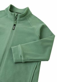 Giacca in pile verde con collare alto, chiusura con zip e maniche lunghe. Presenta dettagli cuciti e una texture delicata.