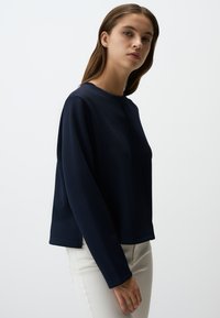 Maglione a maniche lunghe blu navy con una vestibilità comoda, scollatura rotonda e tessuto strutturato. Progettato con cuciture laterali e un orlo dritto.