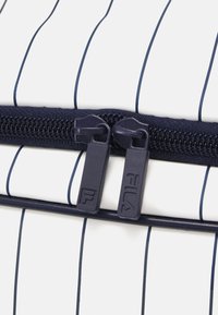 BOLSA CON CREMALLERA con un diseño a rayas blancas y marinas. Presenta dobles tiradores de cremallera en marina con la marca "FILA". Textura suave y material duradero.