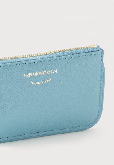 Φωτεινό γαλάζιο υφασμένο δερμάτινο τσαντάκι με φερμουάρ, με χρυσό λογότυπο Emporio Armani και κείμενο "Milano 1981" μπροστά.