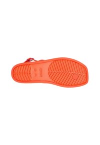 Sandalia de goma naranja con suela texturizada, que presenta un patrón de banda de rodadura pronunciado y una etiqueta de tamaño visible, diseñada para brindar comodidad y agarre.