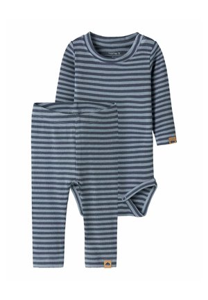 Ensemble bébé deux pièces avec body à manches longues et pantalon en rayures horizontales bleu marine et bleu clair, tissu côtelé et petites étiquettes marron.