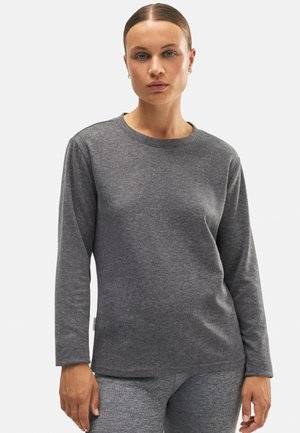 Top gris de manga larga en tejido suave y texturizado con cuello redondo y dobladillo recto. Modelo lleva pantalones grises a juego.