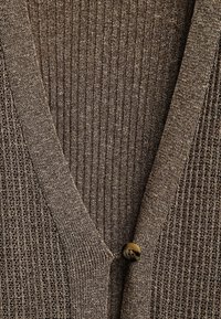 Brauner Strickcardigan mit tiefem V-Ausschnitt, gerippter Textur und einem einzelnen runden Knopfverschluss. Der Stoff hat einen dezenten Glanz.