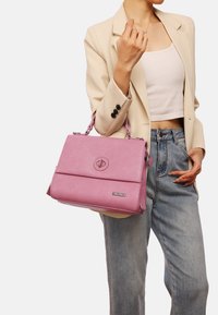 Borsa a tracolla rosa con texture, manici superiori, chiusura frontale e tracolla removibile. Presenta un logo distintivo e una forma strutturata.