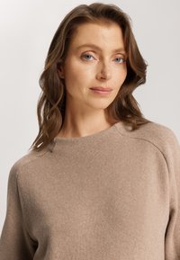 Beige Strickpullover mit Rundhalsausschnitt, Raglanärmeln und einer weichen Textur. Der Stoff zeigt subtile Farbvariationen.
