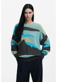 Maglione verde menta con motivi astratti in marrone scuro, blu e beige. Presenta un collo rotondo e una vestibilità ampia con polsini a coste.
