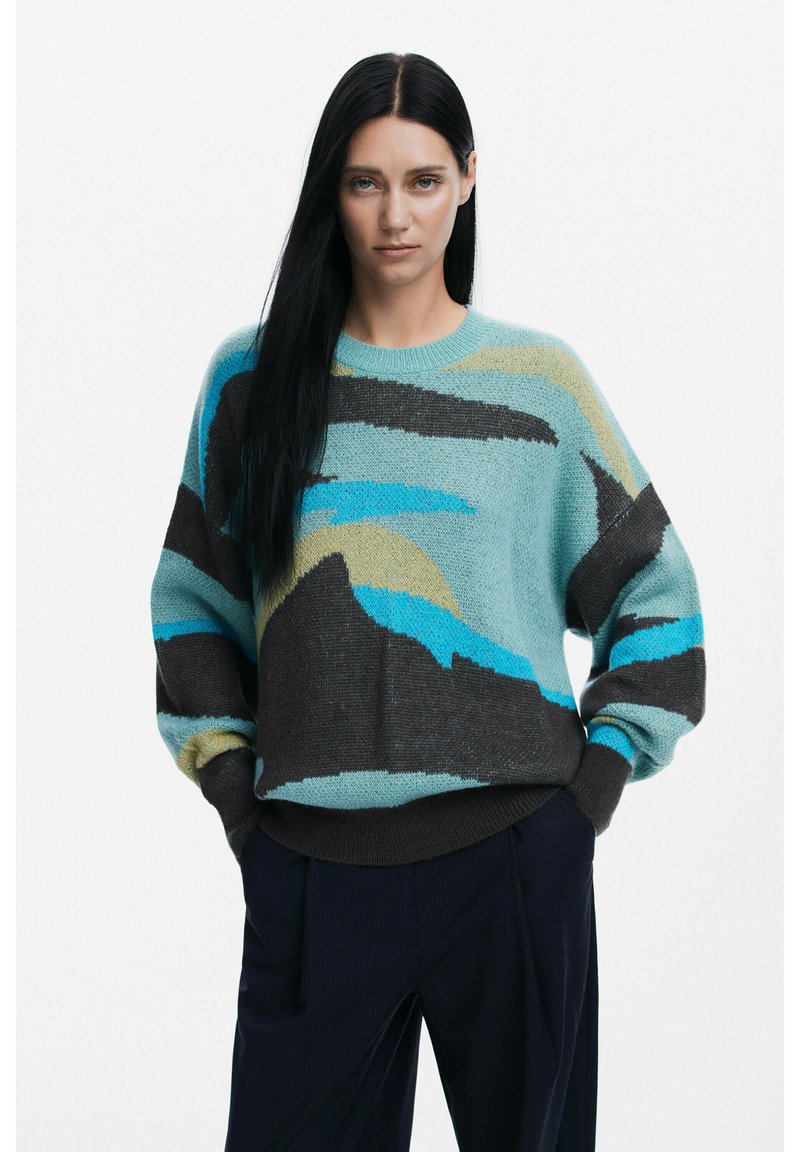 Maglione verde menta con motivi astratti in marrone scuro, blu e beige. Presenta un collo rotondo e una vestibilità ampia con polsini a coste.