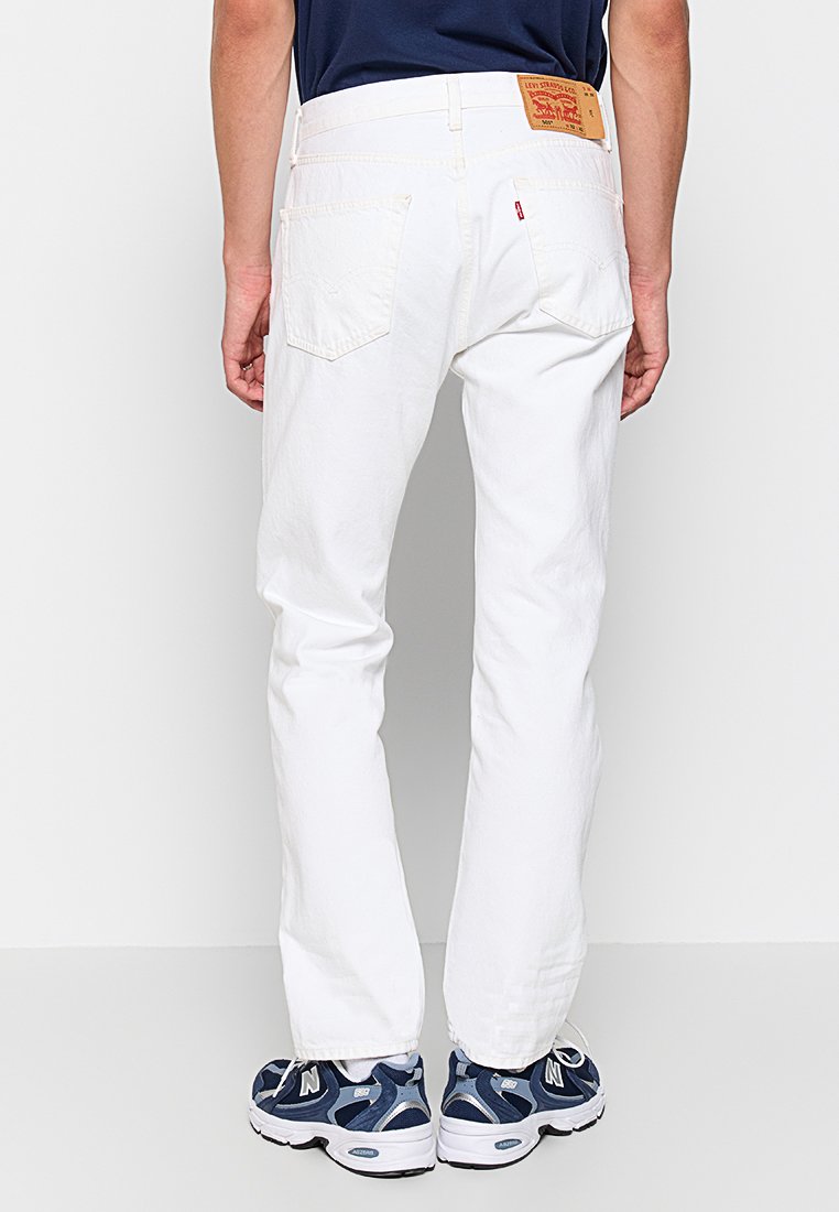 Weiße Jeans mit geradem Bein, ausgestattet mit Gesäßtaschen und einem Leder-Brandpatch am Bund. Glatte Textur und minimalistisches Design.