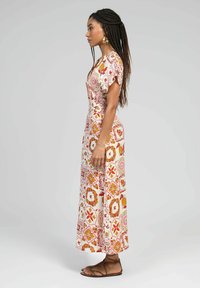 Robe maxi en tissu léger avec un motif floral et géométrique multicolore. Manches courtes et taille ajustée avec un ourlet fluide.