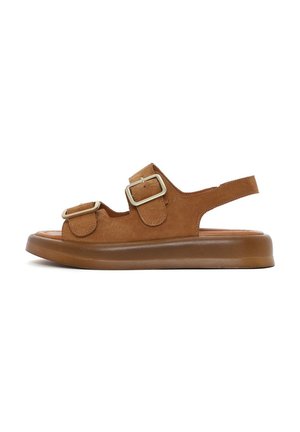 Sandali in suede marrone con due fibbie regolabili, punta chiusa e suola in gomma flessibile con un leggero tacco.