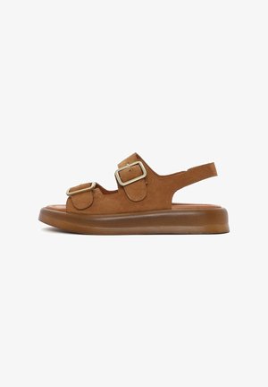 Sandales en suede marron avec deux boucles réglables, un bout fermé et une semelle en caoutchouc flexible avec un léger talon.