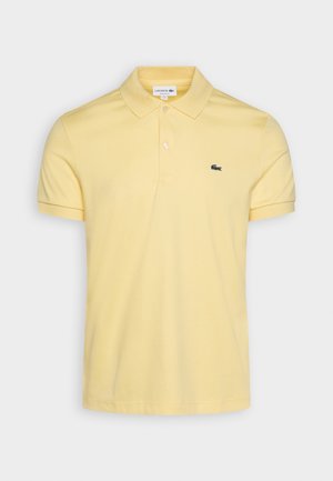 Hellgelbes Polohemd mit kurzen Ärmeln, Kragen und Zwei-Knopf-Leiste, mit kleinem grünen besticktem Krokodil-Logo auf der Brust.