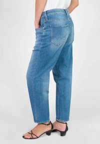 Jeans en denim bleu clair avec une coupe décontractée, dotés d'une taille haute, de cinq poches et d'un léger délavage au niveau des cuisses.