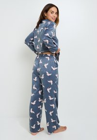 Ensemble de vêtements d'intérieur pour femmes en satin bleu doux, comprenant une veste cropped et un pantalon ample avec un motif d'oiseaux roses.