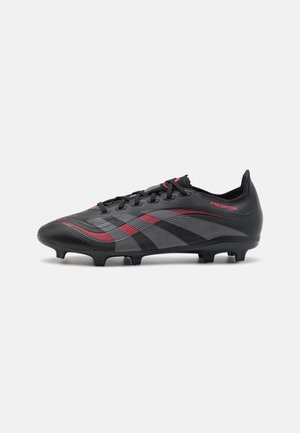 Crampons de football noirs avec un design rouge et gris, présentant un dessus texturé, six crampons et des lacets pour un maintien sécurisé.