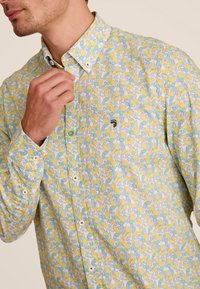 Overhemd met knopen in lichte stof, voorzien van een multicolore patroon van citroenen en bladeren. Witte knopen en een kleine logo-accent op de borst.