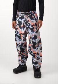 Χρωματιστό, σχέδιο παντελόνι τζόγκινγκ με ένα μείγμα μαύρων, λευκών, ροζ και μπλε στροβίλων. Ελαστική μέση και μανσέτες; φοριέται με μαύρα υποδήματα.