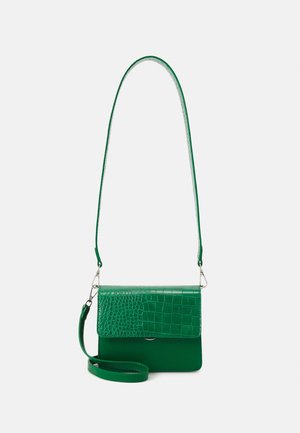 Sac bandoulière en cuir vert avec rabat à texture crocodile et bandoulière amovible sur fond blanc uni.