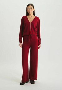 Ensemble bicolore cramoisi comprenant un haut à manches longues en V avec fermeture éclair et un pantalon large, confectionné dans un tissu doux au toucher lisse.