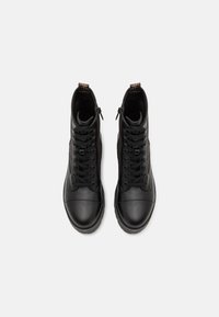 Sneakers neri alla moda in pelle liscia, con design con lacci, chiusura laterale con zip, collo imbottito e suole in gomma.