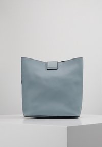 Lichtblauwe leren tote bag met een gestructureerd oppervlak, rechthoekige vorm en een eenvoudige klepsluiting aan de bovenkant.