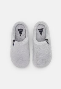 Zapatillas de casa gris con forro de pelo, textura suave, diseño redondeado y etiqueta de logo triangular. Cuentan con un estilo fácil de poner.