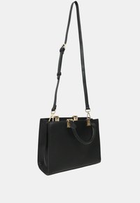 Borsa a mano in pelle nera con finiture dorate, doppio manico superiore e tracolla regolabile. Texture liscia, forma strutturata, design minimalista.