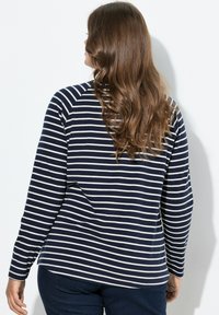 Camicia a maniche lunghe blu navy con righe orizzontali bianche, realizzata in morbido cotone, con orlo arrotondato e maniche a raglan. Design informale adatto per l'uso quotidiano.