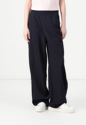 Navy blue, lightweight, wide-leg pants with an elastic waistband. Material appears smooth with a slight sheen. Worn with white sneakers.