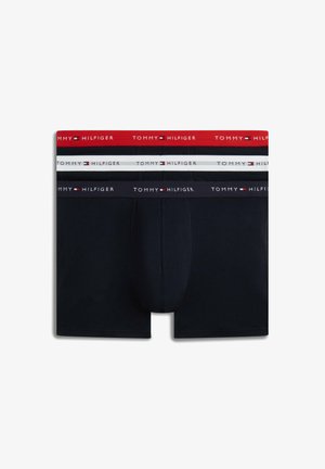 Trzy pary męskich bokserek w kolorach granatowym, czarnym i białym, każda z nich posiada brandingowaną gumkę Tommy Hilfiger w kolorach czerwonym, białym i granatowym.