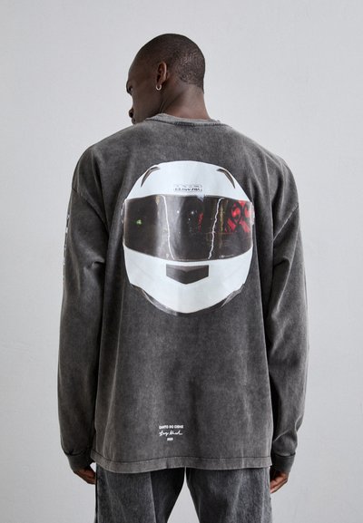 Gray oversized sweatshirt featuring a graphic of a racing helmet on the back. Smooth fabric with a relaxed fit and long sleeves.
