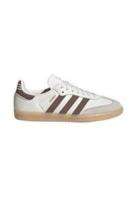 Baskets blanches Adidas Samba avec des bandes marron, une semelle en gomme et le texte doré "SAMBA" sur le côté, vues de l'intérieur.