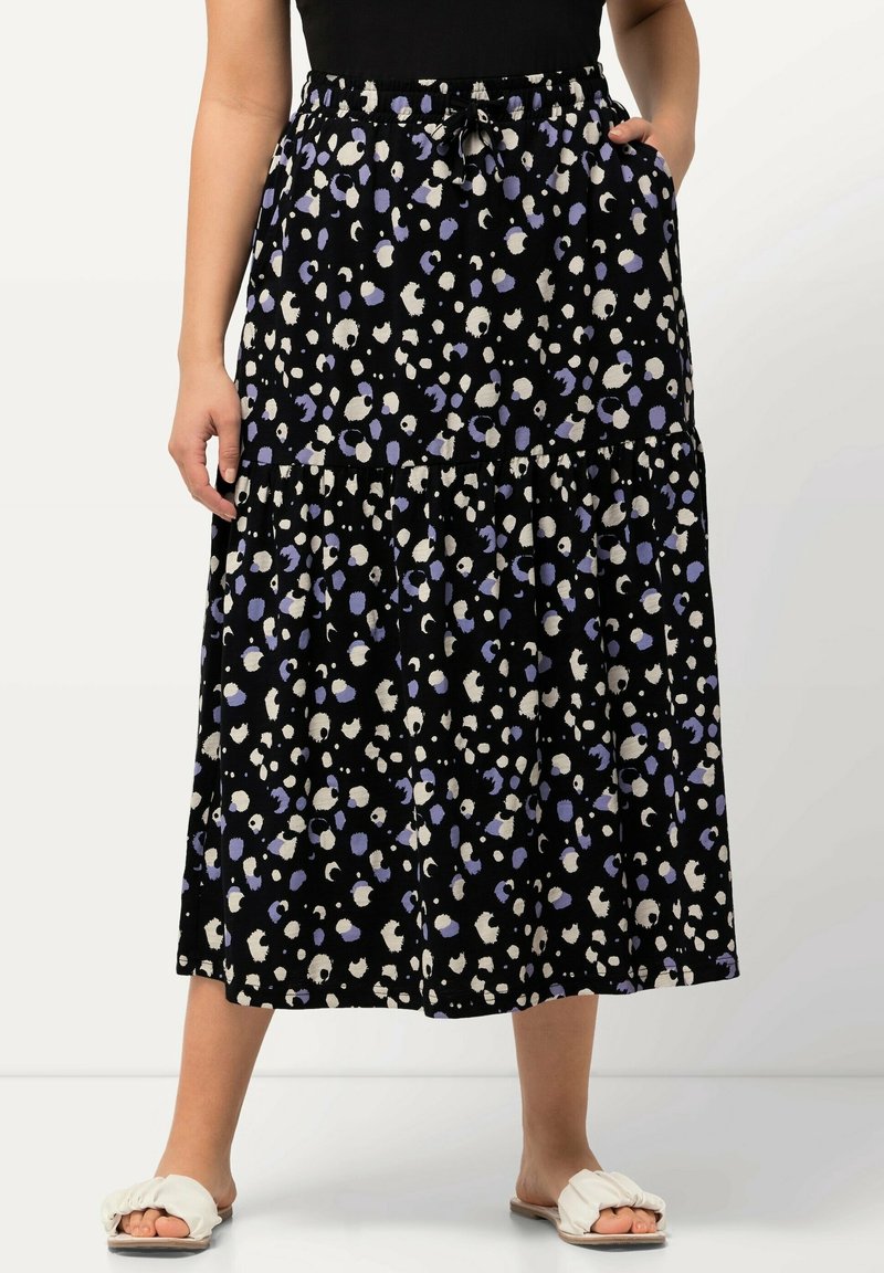 Musta kerrostettu hame, jossa on kiristysvyö, valkoisilla ja laventelin sävyisillä abstrakteilla pilkuilla. Kevyestä kankaasta valmistettu, mukava istuvuus.