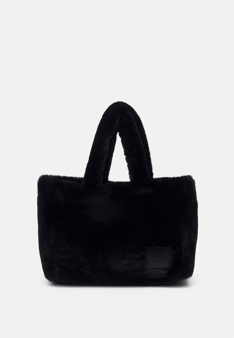 Sac fourre-tout rectangulaire noir avec une texture douce et pelucheuse, des poignées courtes et un petit écusson logo embossé sur la partie inférieure avant.