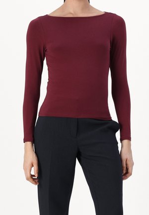 Pitkähihainen, tummanpunainen yläosa, jossa on neliömäinen pääntie ja sileä kangas. Yhdistetty tummiin, räätälöityihin housuihin. Yksinkertainen muotoilu, ei näkyviä kuvioita.