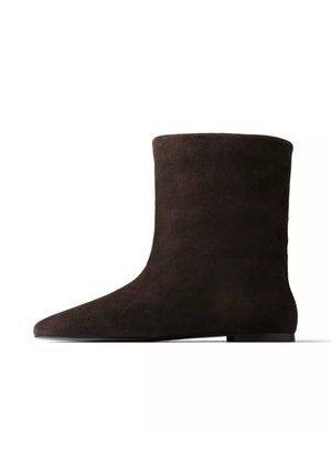 Donkerbruine suède enkellaars met een platte zool en een afgeronde neus, rechts zijaanzicht op een witte achtergrond.