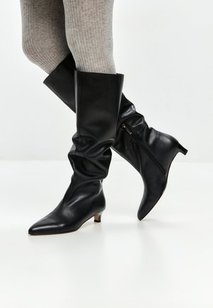 Stivali alti in pelle nera con punta affusolata e tacco basso a blocco. Presentano un design morbido e una zip laterale per una facile indossabilità.