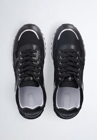 Sneaker sportive nere in materiali mesh e pelle, design con lacci, dettagli riflettenti e accenti grigi a contrasto.