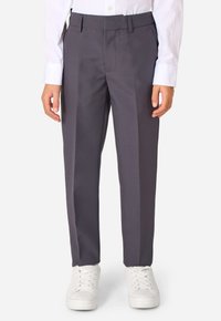 Graue Anzughose mit flachem Vorderteil, Gürtelschlaufen und taillierter Passform, kombiniert mit weißen Sneakers und einem Langarmshirt.