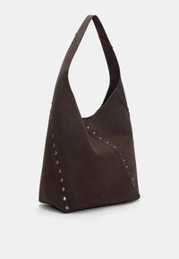 Sac en cuir brun de style hobo avec une forme décontractée, un design angulaire et des clous argentés sur un côté, avec une seule bandoulière arrondie.