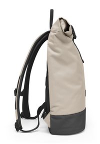 Sac à dos beige clair avec une fermeture enroulable, matériel noir, bretelles rembourrées et réglables, et un panneau inférieur texturé noir.