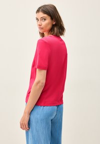Fuchsia kortærmet t-shirt med rund hals og en afslappet pasform, kombineret med lyseblå vidde bukser. Glat, letvægtsstof.