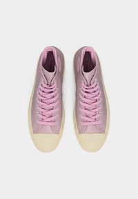 Ζευγάρι ροζ ψηλά αθλητικά παπούτσια με κρέμα σόλες από καουτσούκ και κορδόνια, εμφανιζόμενα από πάνω σε λευκό φόντο.