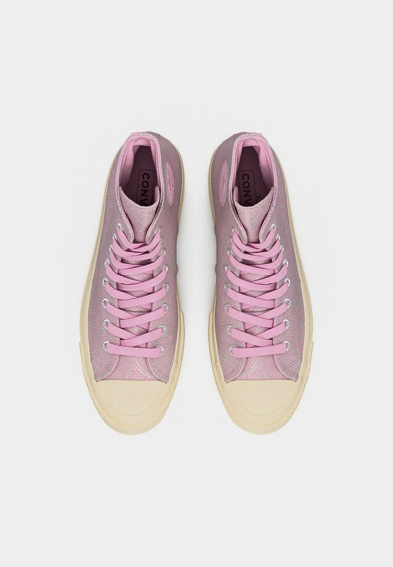 Een paar roze hoge sneakers met crèmekleurige rubberen zolen en veters, gezien van bovenaf op een witte achtergrond.